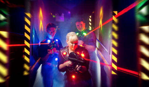 Kids playing laser tag in a bright neon arena